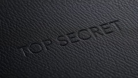 Embossed top secret on black pebbled leather closeup for confidential branding