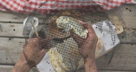 Hands pulling rustic flatbreads during outdoor picnic on wooden table with gingham cloth