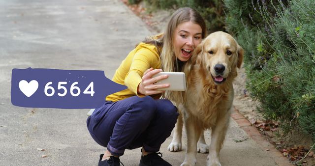 Happy young woman is taking a selfie with her golden retriever dog in a park. She is smiling and holding her phone while crouching next to the dog. The selfie has received many likes on social media as indicated by the like count overlay shown in the image. Perfect for use in social media, outdoor activities, pet care advertisements, and sharing joyful moments with pets.