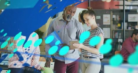 Woman Showing Tablet to Colleague in Collaborative Open-Plan Office with Teal Glass Decals