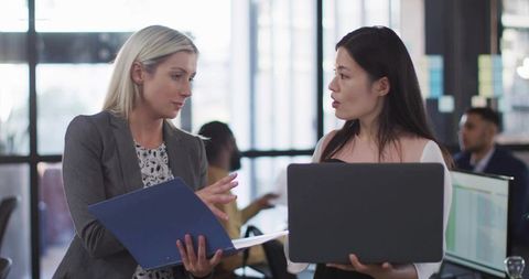 Professional Women Discussing Report in Modern Office