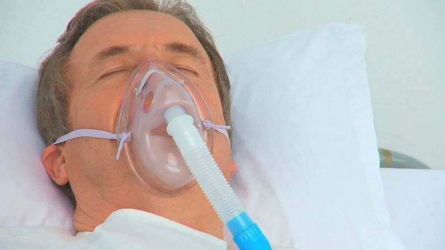 Video depicts an unconscious male patient laying in a hospital bed with a respirator. Useful for medical articles, emergency healthcare discussions, intensive care unit visuals, and healthcare provider resources focusing on patient treatment and hospital care.