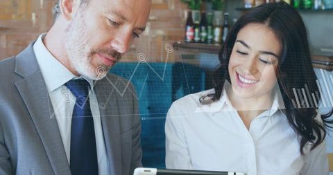 Business team reviewing tablet with financial graphs overlay, collaborating in lounge