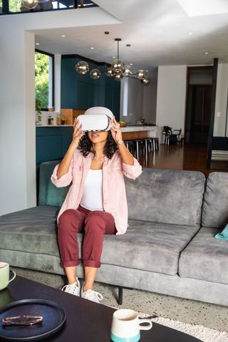 Indian woman exploring virtual reality on modern sofa in contemporary open-plan home