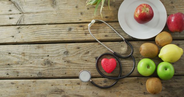 Fruits arranged on rustic wooden table with stethoscope representing heart health and wellness. Useful for topics related to nutrition, healthy eating, heart health, medical advice, and lifestyle improvement. Suitable for health blogs, wellness websites, nutritionist materials, and healthcare promotions.