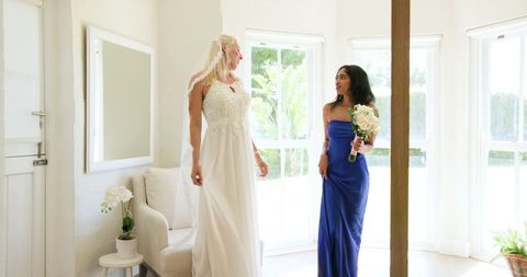 Happy Bride with Bridesmaid Preparing for Wedding Ceremony at Home