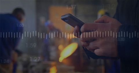 Technician using smartphone in industrial workshop with furnace