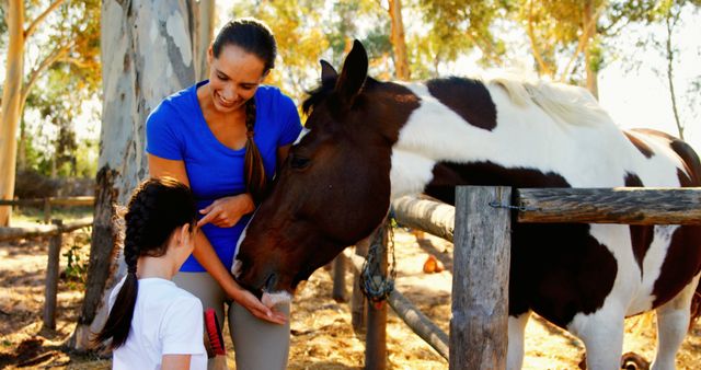 A young woman and a girl interact with a horse outdoors, with copy space. Their bonding moment with the animal reflects a connection with nature and the joy of equestrian activities.