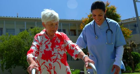 Nurse assisting senior patient outdoors in nursing home garden