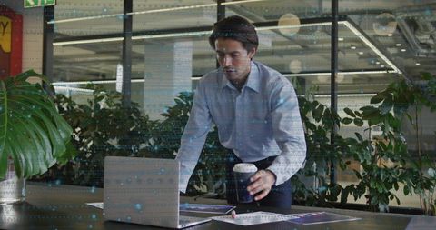 Businessman in Modern Office Analyzing Printouts While Drinking Coffee