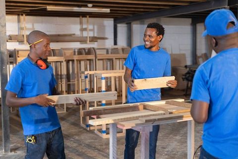 African american carpenters collaborating on wooden planks at workshop workbench