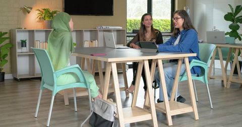 Muslim woman in hijab collaborating with diverse colleagues at modern coworking table