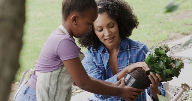 Mother and daughter bonding experience through gardening. Ideal for content related to family activities, teamwork, nurturing relationships, and outdoor hobbies. Great for blogs, advertorials on family-oriented products, educational content on gardening, and health and wellness articles promoting outdoor activities.