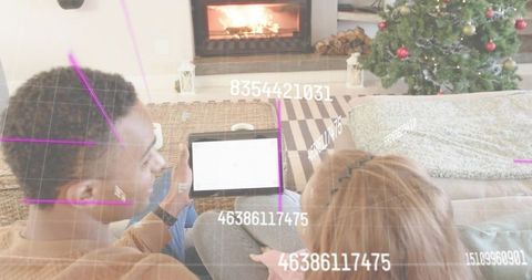 Couple using tablet in cozy living room with augmented reality grid and festive fireplace