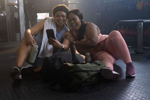 African american friends laughing after gym session, checking phone and hydrating