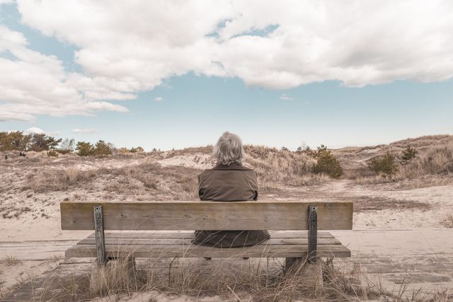 Elderly Woman Sitting on Bench Looking at Peaceful Sand Dunes - Download Free Stock Images Pikwizard.com