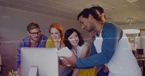 Young team collaborating around desktop and tablet reviewing data visualization workflow