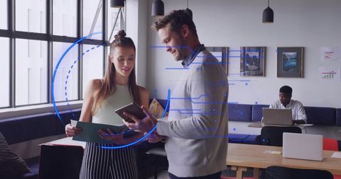 Coworkers collaborating with tablet and documents in openplan workspace with digital hud