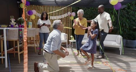 Multigenerational Family Celebrating Birthday on Covered Backyard Patio with Balloons