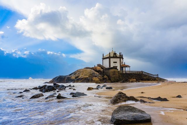 Iconic Chapel of Senhor da Pedra perched on rocky formations in Porto, Portugal. Ideal for travel brochures, nature and architecture magazines, websites showcasing coastal tourism, and scenic photography collections.