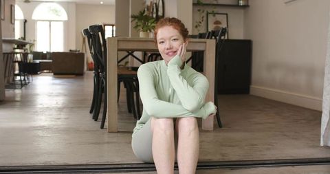 Woman sitting on threshold, smiling, relaxed lifestyle in modern airy home interior