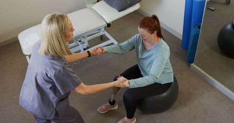 Prosthetist Assisting Patient Exercising with Prosthetic Limb in Therapy