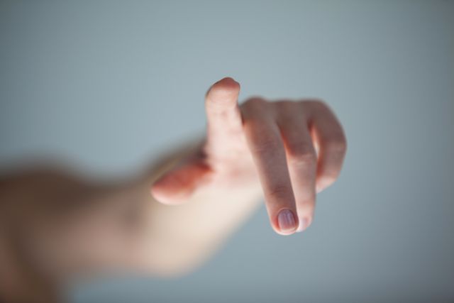 This image shows a woman's hand reaching out and touching an invisible screen against a grey background. It is ideal for illustrating concepts related to technology, virtual interfaces, and modern innovations. Perfect for use in articles, presentations, and advertisements focusing on futuristic technology and human-computer interaction.