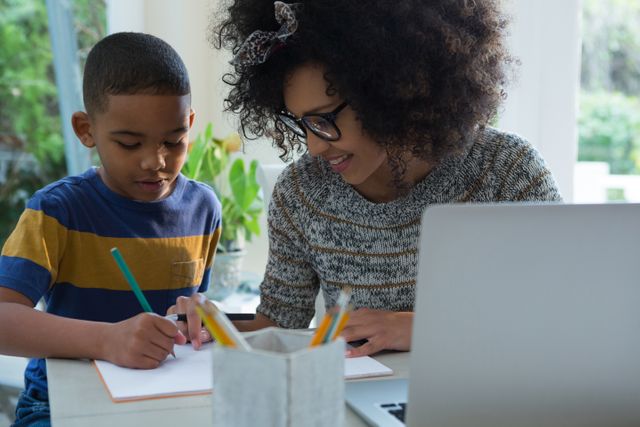 Mother assisting her young son with his homework at home, fostering learning and support. Perfect for illustrating education, homeschooling, parent-child interaction, and family values. Great for use in articles, blogs, advertisements, and educational materials.