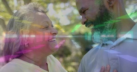 Senior couple smiling and leaning in sunlit park with colorful digital light overlays