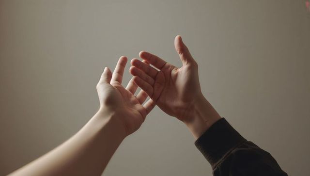 Reaching Hands Connecting Over Neutral Background Conveying Support, Trust, Vulnerability