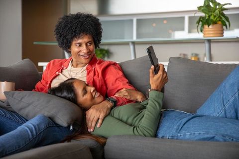 Diverse Couple Relaxing and Enjoying Smartphone on Sofa