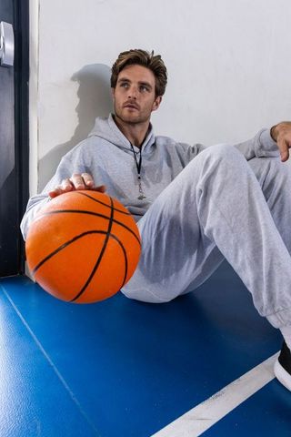 Athletic Young Man in Grey Tracksuit Holding Basketball on Court