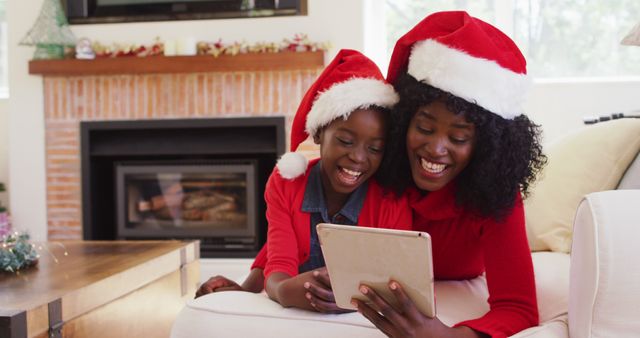 Mother and daughter wearing Santa hats using tablet in living room - Download Free Stock Images Pikwizard.com