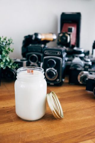 Jar candle on wooden table with vintage cameras