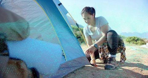 Female camper securing tent stake on outdoor adventure