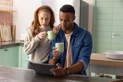 Couple Enjoying Morning Coffee and Exploring Tablet in Modern Kitchen