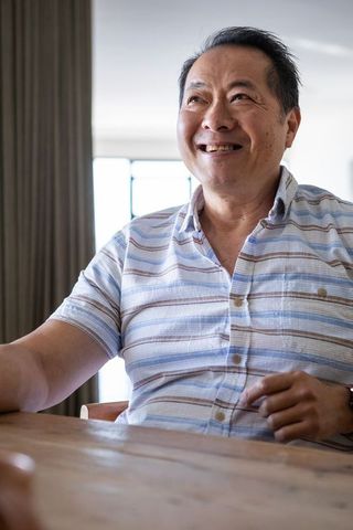 Smiling Senior Asian Man Sitting at Home Dining Table