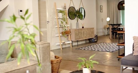 Scandinavian boho living room showcasing neutral decor, plants, wood furniture, patterned rug