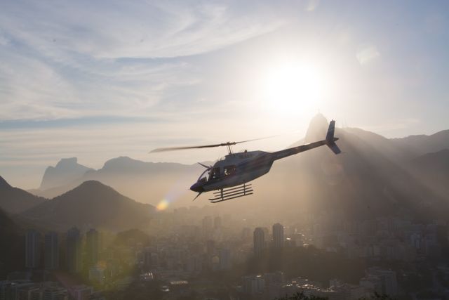 Helicopter Flying Over Urban City at Sunset with Mountains in Background - Download Free Stock Photos Pikwizard.com