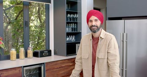 Man in modern kitchen wearing red turban enjoying culinary art