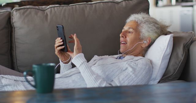 Senior Woman Relaxing on Couch with Smartphone and Earphones - Download Free Stock Images Pikwizard.com