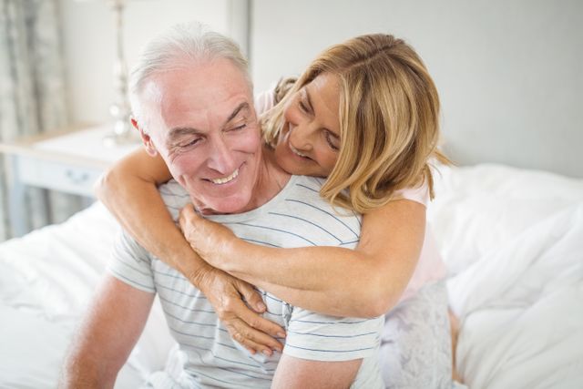 Happy senior couple embracing each other on bed in bedroom