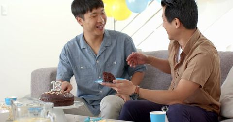 Father and son celebrating 18th birthday with cake at home