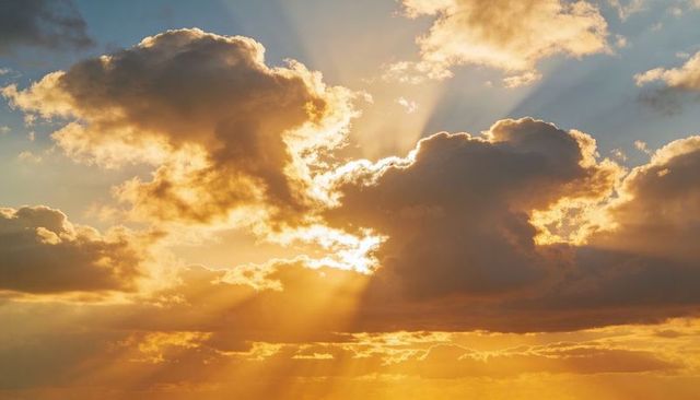 Golden crepuscular rays streaming through dramatic cumulus clouds sunrise goldenhour glow