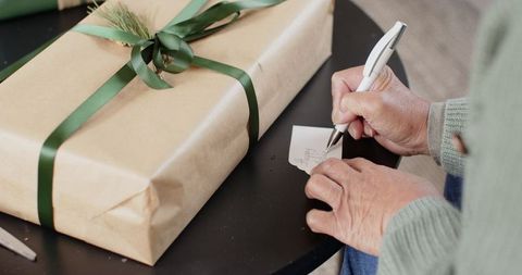 Senior Woman Writing Gift Tag on Kraft Paper Wrapped Present