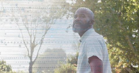 Pensive man gazing upward in sunlit park with glitch-pattern overlay and golden-hour glow