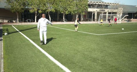 Coach Supervising Youth Soccer Practice on Sunny Field