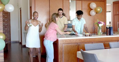 Diverse Friends Preparing Meal Together During Home Gathering