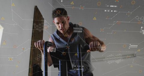 Man pedaling air bike wearing sleeveless zip-up hoodie showing intense cardio focus