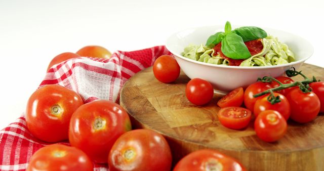 This image features a close-up view of a bowl of fresh pasta garnished with basil and cherry tomatoes, placed on a wooden board. Adjacent to the pasta, there are whole and vine tomatoes, adding vibrant color to the scene. Ideal for use in food blogs, Italian cuisine articles, healthy eating promotions, organic recipe books, and culinary advertisements, illustrating fresh and natural ingredients.